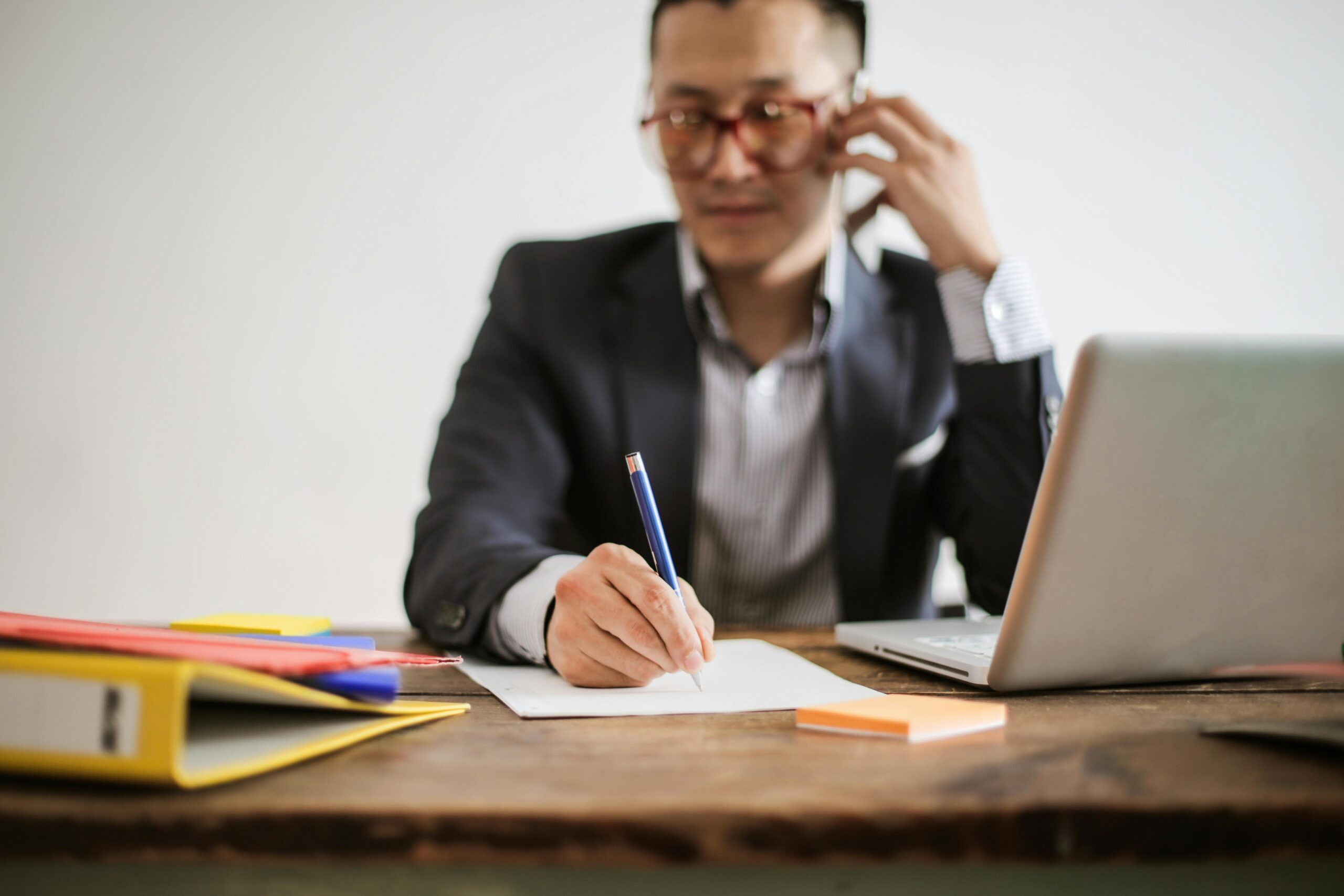 person on phone with pen and paper