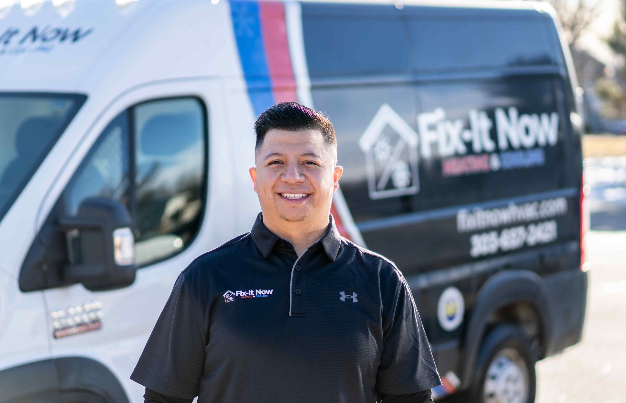 smiling HVAC technician in front of company van